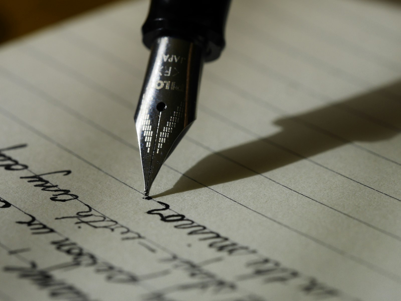 A notebook, pen, and laptop on a clean writing desk