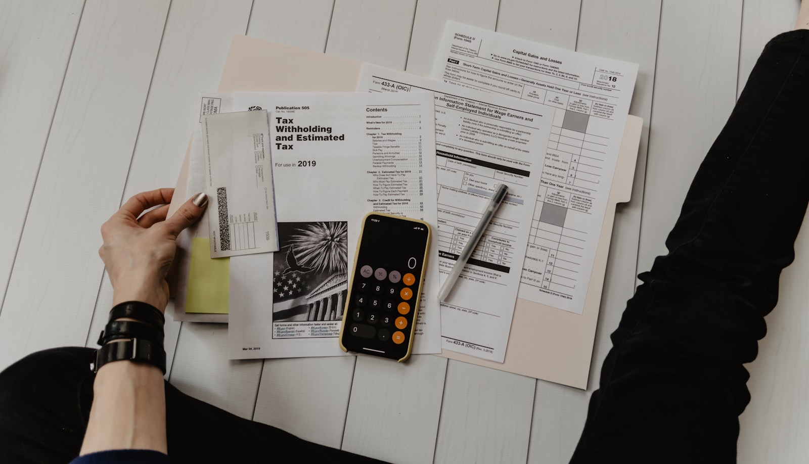 Paper bills, a calculator, and a notebook on a desk