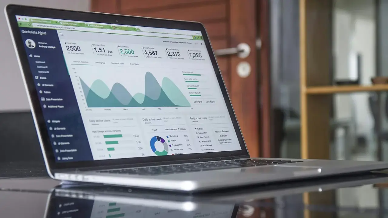 A laptop displaying analytics charts on a glass-top table