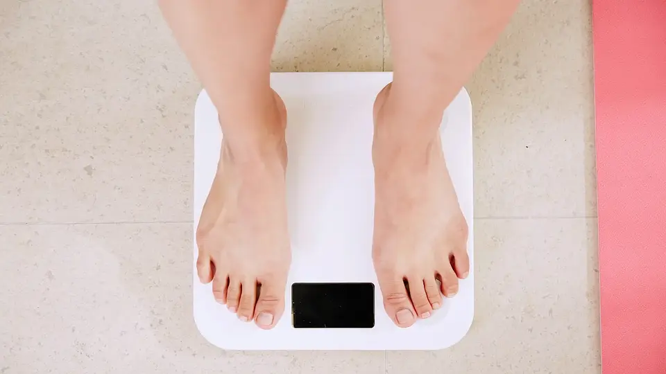 A person standing on a white digital bathroom scale
