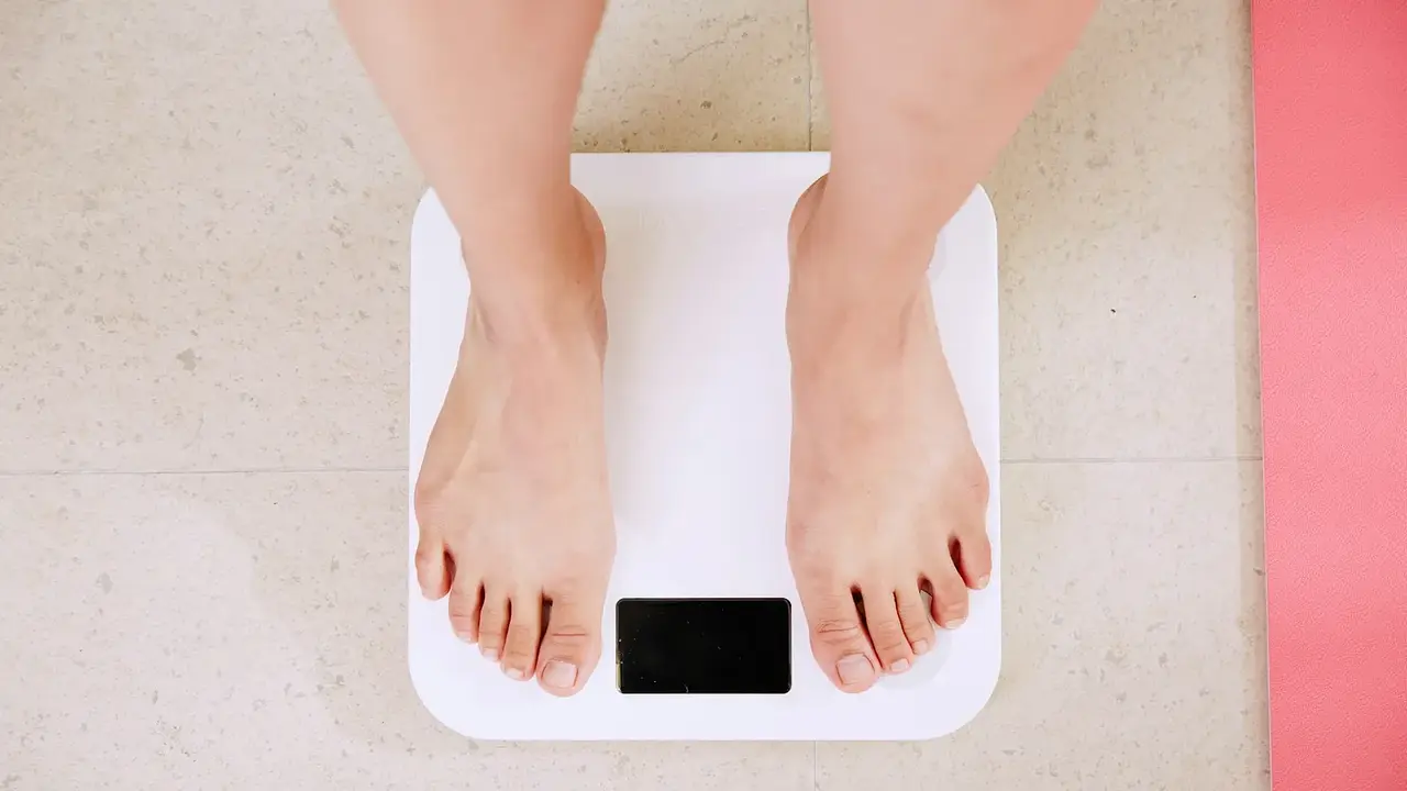A person standing on a white digital bathroom scale