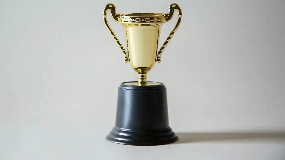 A yellow and white trophy against a dark background