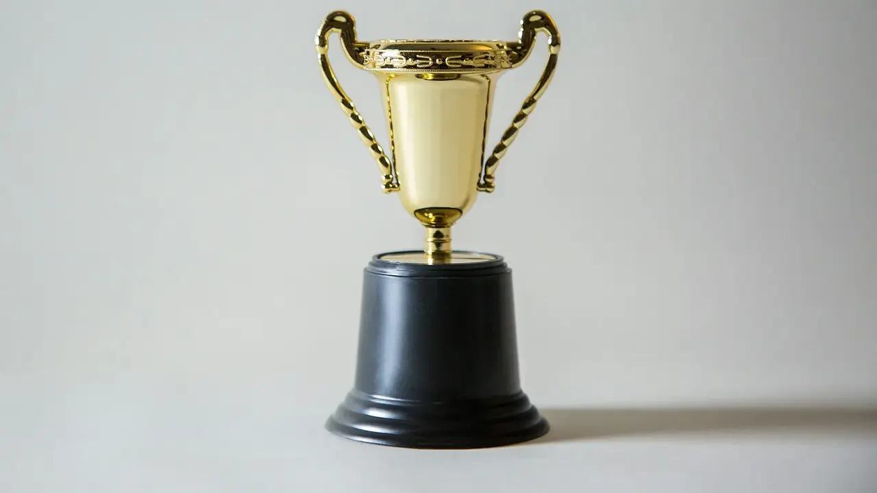 A yellow and white trophy against a dark background