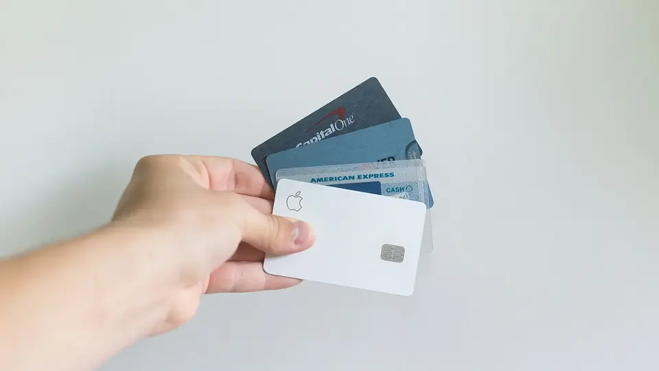 A hand holding several payment cards against a plain background
