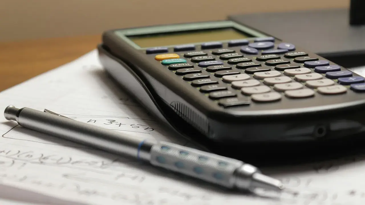 A calculator and pen on top of compensation paperwork